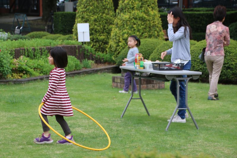 中庭の芝生でフラフープや水鉄砲で遊ぶ子供たち。